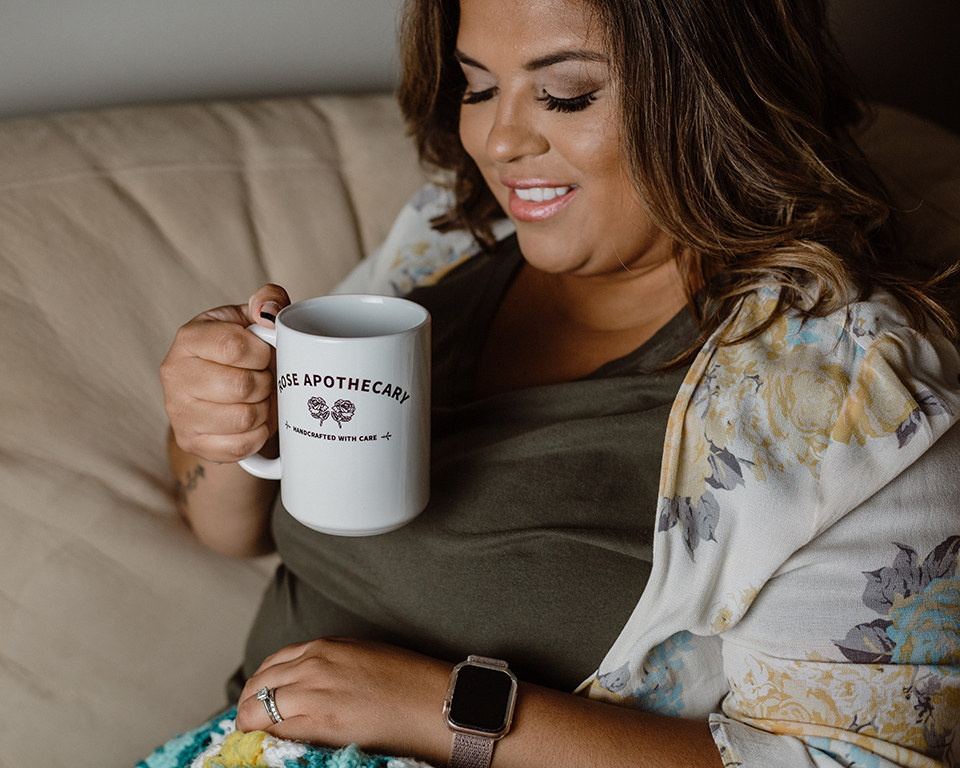 A woman sitting on a couch holding a white mug
